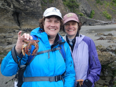Two participants smile and one is holding either a dead crab or a crab carapace in Olympic National Park