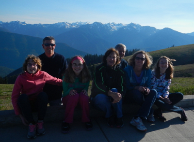 A family that includes three generations pose for a photo with a view from Hurricane Ridge