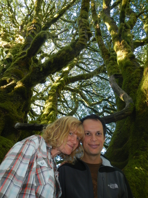 Looking up at a smiling couple with a huge mossy Bigleaf Maple in the background