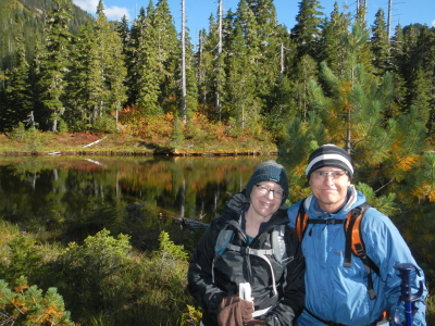 A couple stands next to a reflection lake with beautiful fall color