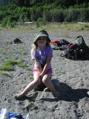 Young girl with a sun hat seated on a rock in an Elwha River sandbar